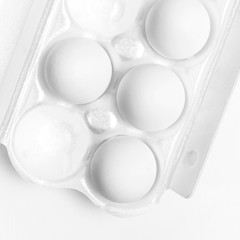 White chicken eggs in white packaging on light background top view flat lay copy space. Eggs in box, natural healthy food and organic farming concept. Creative food minimalistic background, Easter