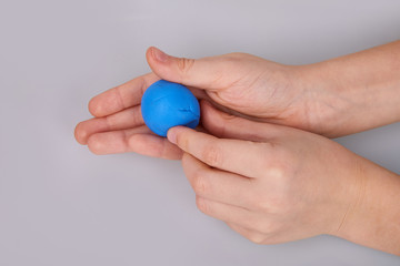 The process of play dough modeling, the child's hands sculpt figures. Play dough in preschool or nursery for education concept. Piece of blue plasticine in the hand. 