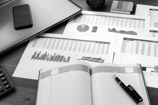 Open leather notebook, drawings, charts, phone, calculator, pencil and laptop on the desk in the office. Business and Finance.