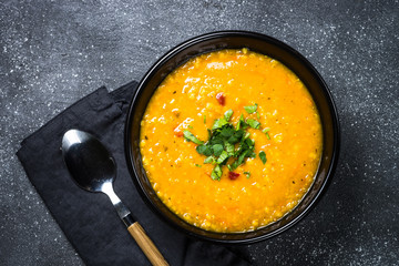 Red lentil soup on black top view.