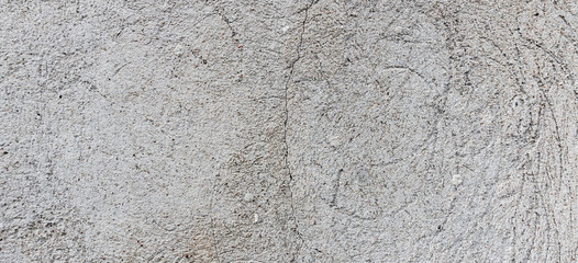 Obraz na płótnie Canvas Dark plaster wall with dirty cracked scratched background. Old cracked weathered shabby retro vintage brickwall with peel grey stucco texture banner background