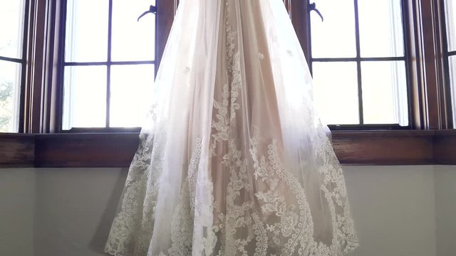 Slow Motion Reveal Of Elegant Wedding Dress Hanging In Window Frame, Backless Design, White Wedding Gown, Pearl Accents