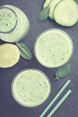 Refreshing green cucumber, yogurt, mint and lemon smoothie in glasses, photographed overhead on slate (Selective Focus, Focus on the drinks) (Digitally Altered: Toned Image)