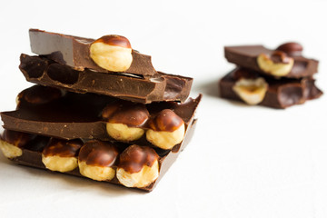 Hazelnut dark chocolate pieces tower on white background.