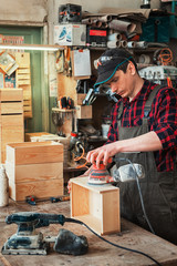 Worker grinds the wood box of angular grinding machine