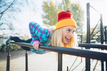 Young beautiful woman doing push ups on parallel bars at calisthenics park, looking off the camera