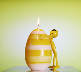 big candle egg and toy man, cheerful situation, smile, burning candle