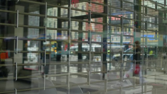Steel security gate of a closed store in Midtown Manhattan, NYC while pedestrians walk out of focus in the background.
