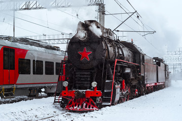 steam locomotive and modern multiple-unit train stand nearby at station