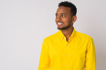 Happy young handsome African businessman with yellow shirt thinking