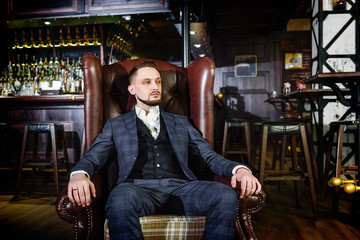 Fototapeta na wymiar stylish man in a suit sits in a chair in a pub