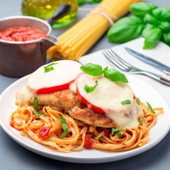 Chicken caprese with tomato and mozzarella cheese, served with linguine, tomato pasta sauce and basil, square