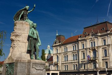 Bronze sculpture of national poet Preseren Monument with Muse and historic Kresija building with government offices and dome of Ljubljana Cathedral