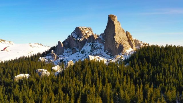 Drone moving arround summit rocks at sunset. Lady's Stones in Rarau mountains, aerial winter view of Rarau top.