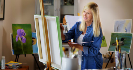 Woman painting art on canvas in artist studio.