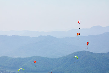 Flying on a paraglider. Beautiful view with mountains and colorful paragliders. Extreme vacation travel
