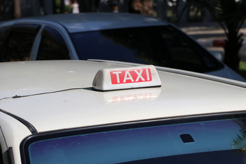 Taxi light sign or cab sign in white and red color with white text on the car roof at the street...
