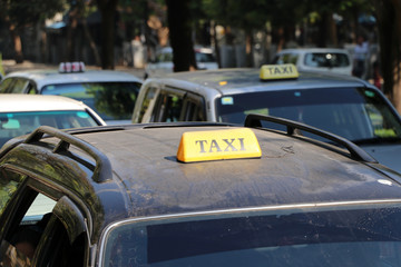 Taxi light sign or cab sign in yellow color with black text on the car roof at the street blurred background.
