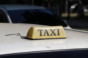Taxi light sign or cab sign in drab brown color with black text on the car roof at the street blurred background