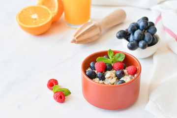 oatmeal with organic blueberries and raspberries, fresh orange juice and grapes. light background, selective focus and copy space, Breakfast concept. diet, healthy food