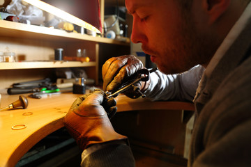 Jeweler measuring a ring with compass divider in a workshop lith with warm light