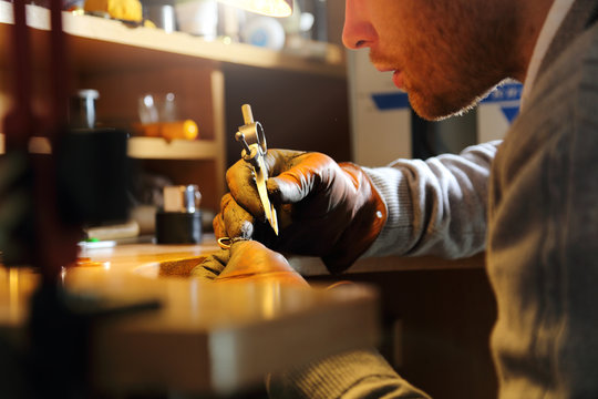 Jeweler measuring a ring with compass divider in a workshop lith with warm light