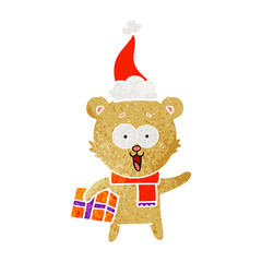laughing teddy  bear with christmas present wearing santa hat