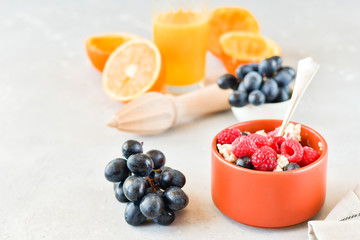 oatmeal with organic blueberries and raspberries, fresh orange juice and grapes. light background, selective focus and copy space, Breakfast concept. diet, healthy food