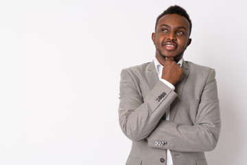 Portrait of happy young African businessman in suit thinking