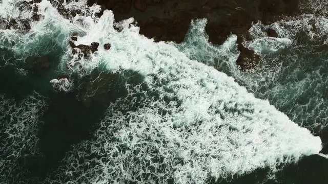 Top down aerial shot, showing the coastline of Ecuador, with waves crashing on rocks.