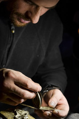 The watchmaker holds the silver case of a vintage pocket watch in his workshop