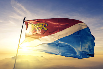 Primorsky Krai of Russia flag waving on the top sunrise mist fog