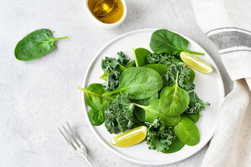 flat lay green salad of organic spinach and kale leaves with lemon juice and olive oil. diet menu...