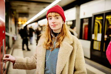 junge Frau kauft auf dem Bahnsteig eine Fahrkarte
