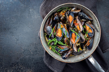 Traditional barbecue Italian blue mussel in white wine creme sauce with salicornia and vegetable in as top view in a casserole