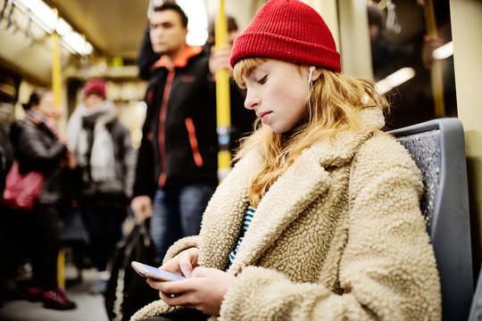 junge Frau, M&auml;dchen, Teenager, sitzt mit ihrem Smartphone, Handy, in der U-Bahn
