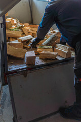 Mann lädt Holzscheite aus einem Anhänger aus