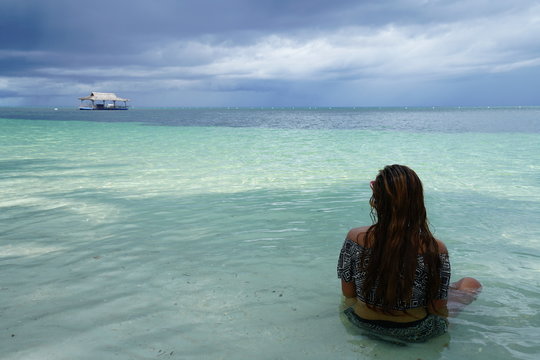 Woman sitting, looking out at the ocean in Siquijor Island, Philippines