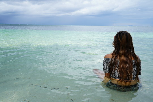 Woman sitting, looking out at the ocean in Siquijor Island, Philippines