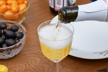 Pouring champagne from a bottle into a glass on the background of red caviar, close-up