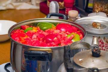 Cut into pieces vegetables - bell peppers, tomatoes, etc. - in a shiny metal pan on the kitchen table