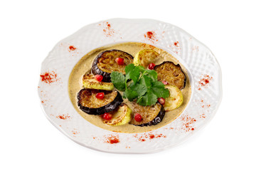 Plate of grilled eggplant and squash slices served with sauce isolated at white background.