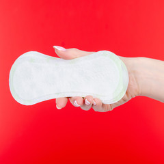 Sanitary menstruation pad panty liners in hand on red background