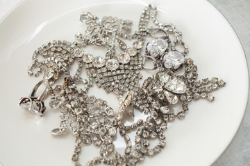 Many sparkling jewelery on a white plate The concept of luxury life, wealth, glamor, fashion and weddings