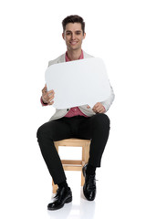 happy young elegant man sitting and holding a speech bubble