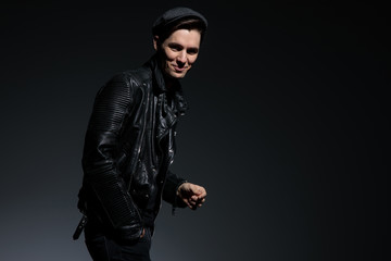 Naklejka na ściany i meble laughing young fashion man in leather jacket and hat