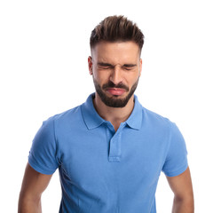 Childish young man wearing a light blue polo feeling upset