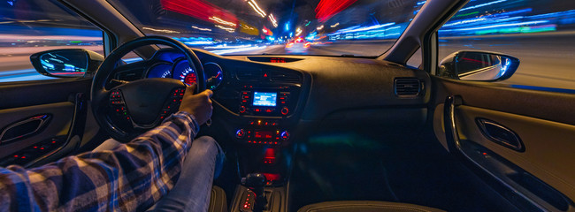 driving a car at night at high speed view from the car. blurred city. one hand driving
