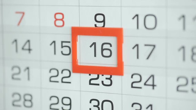 Woman's hand in office changes date at wall calendar. Changes 15 to 16