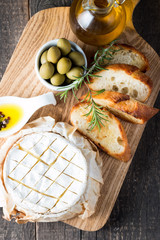 Baked camembert cheese. Fresh Brie cheese and a slice on a wooden board with nuts, honey, rosemary,...